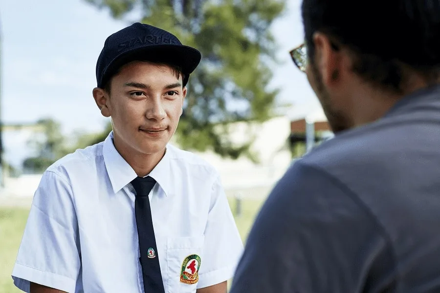 close up of student with hat talking to youth worker