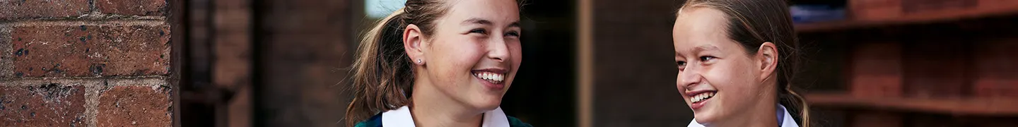 Two laughing girls sitting together at school.