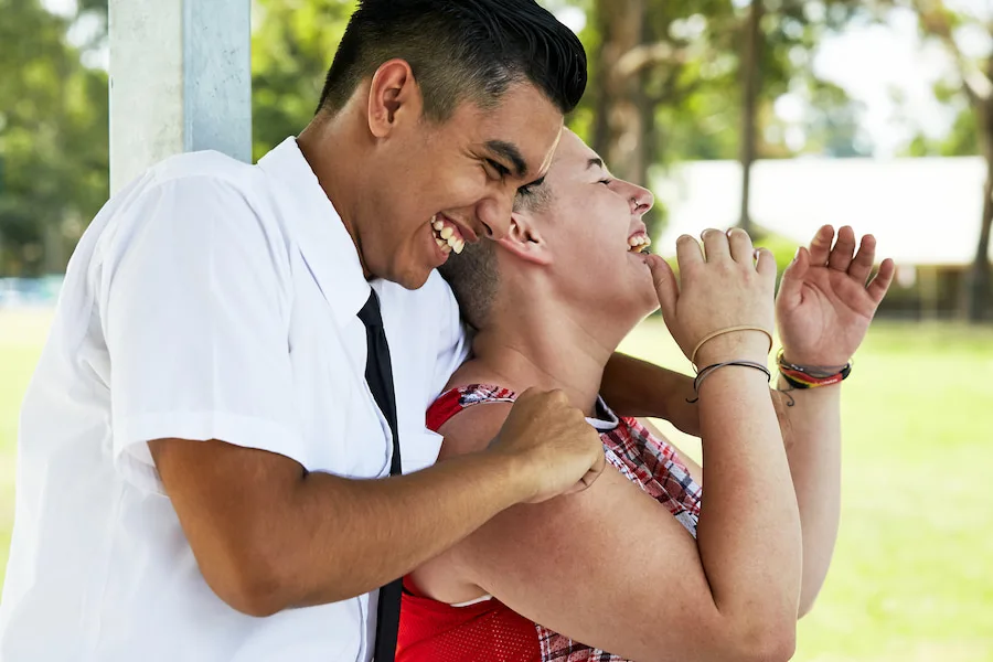 Two students laughing and hugging