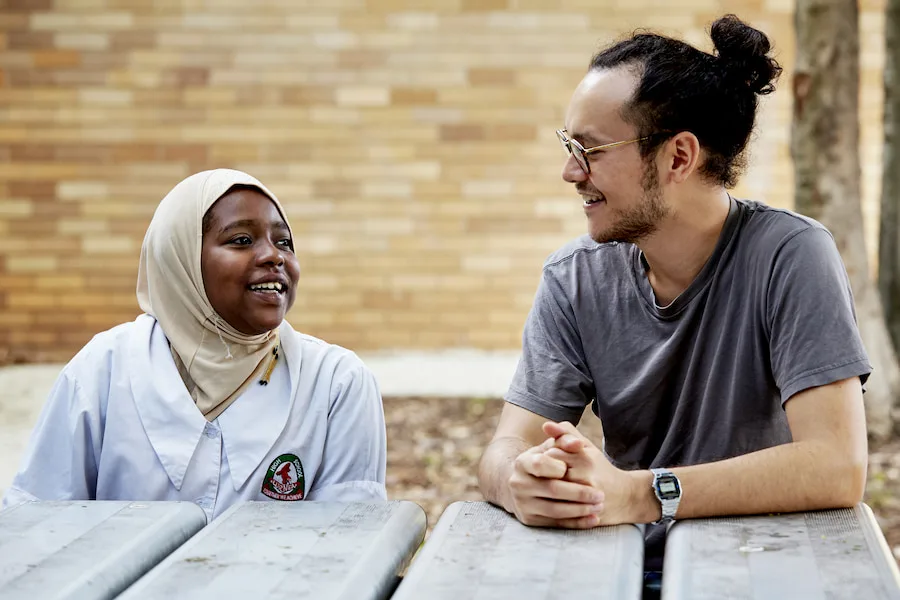 Student and teacher sitting at a table talking outside