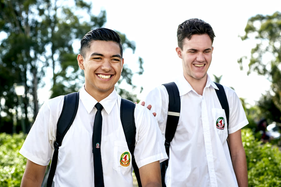 Image of two teen boys in school uniform. They are laughing and smiling.