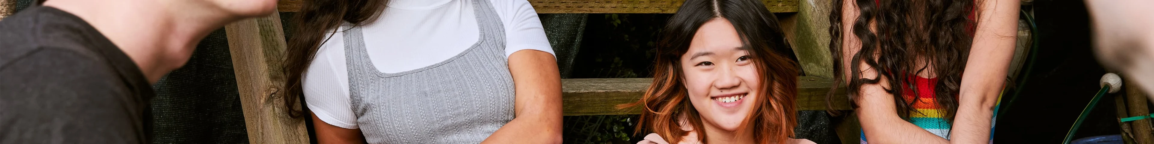 Image of a smiling teen girl sitting with her friends.