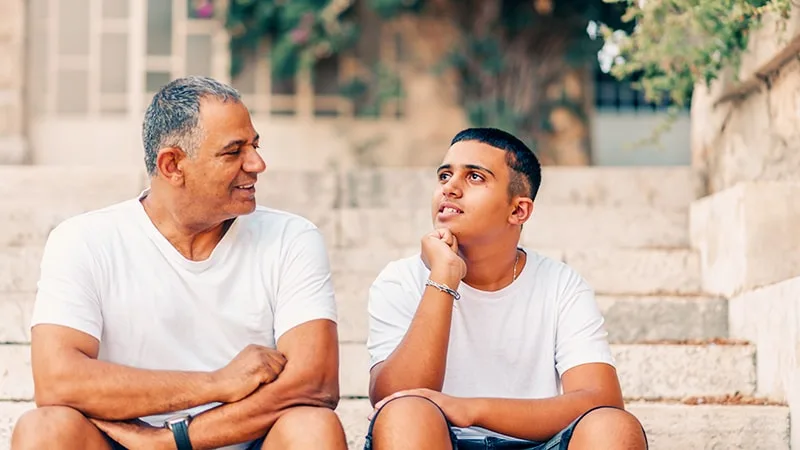 father and son talking sitting on steps