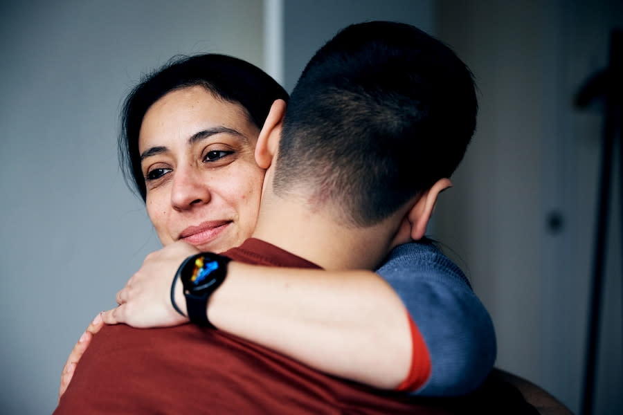 Image of a woman hugging her son with a slight smile on her face.