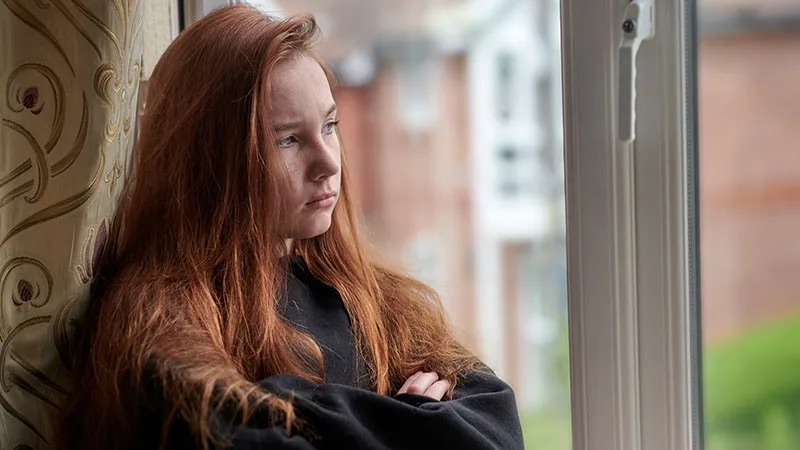 Teenage girl with red hair looking upset