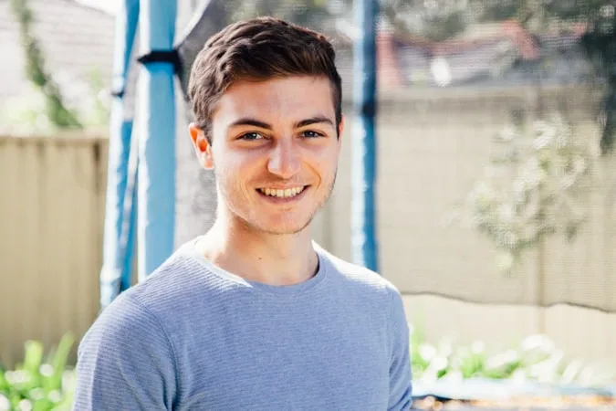 Boy in grey shirt smiling at camera