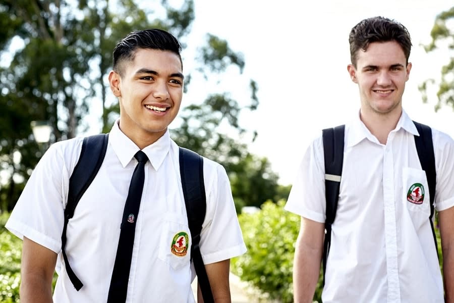 Two boys in school uniforms walking and smiling