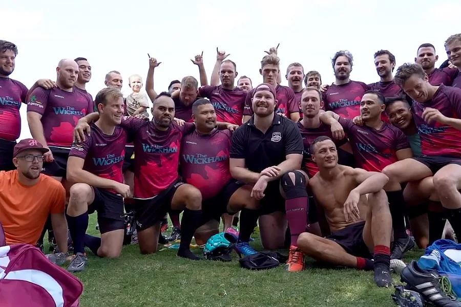 brisbane hustlers male football team in dark purple and pink team uniform with arms around each othe