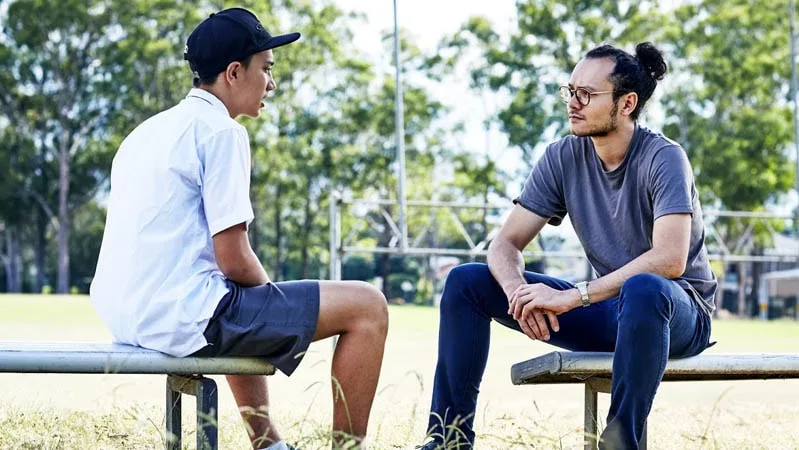 man talking to boy on seats