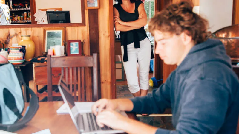 mother watching over son on computer