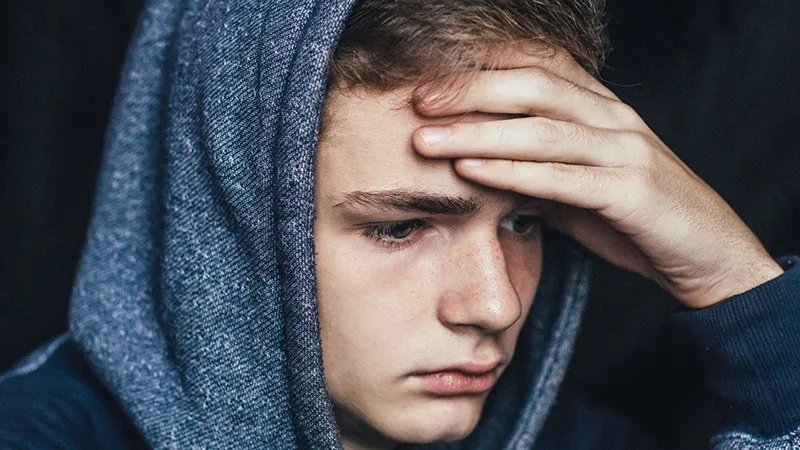 Teenage boy with head in hand