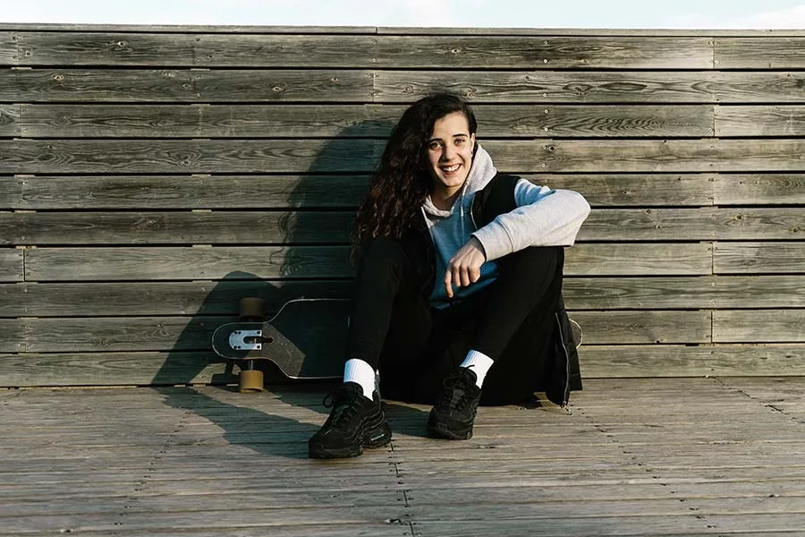 teenage girl sitting on the ground holding skateboard