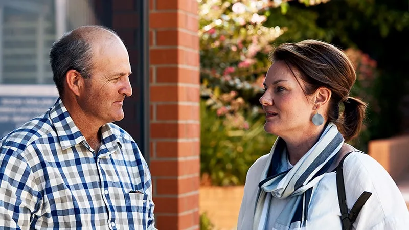 man and woman talking to each other outside building