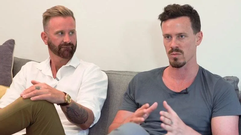 two fathers sitting on a lounge talking