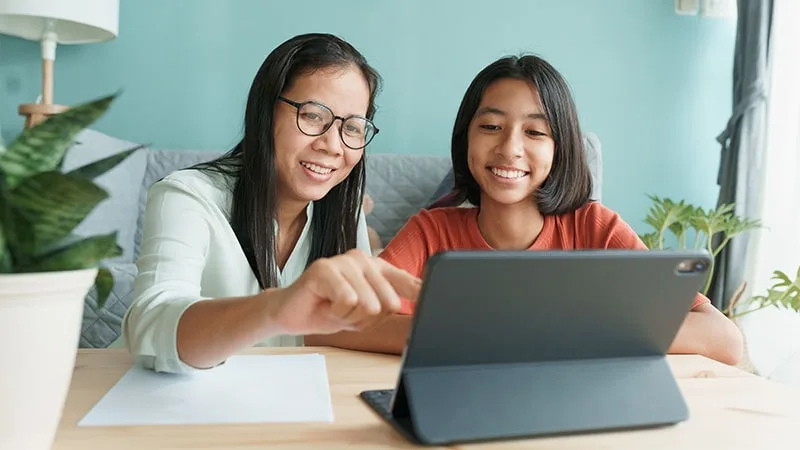 Mother and daughter on ipad and smiling