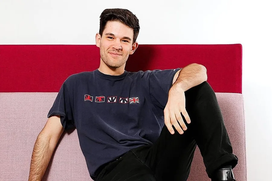 young man smiling sitting against red and pink wall