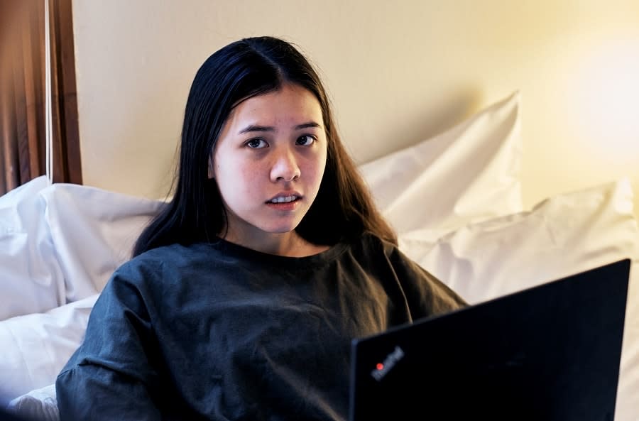 girl using laptop in bed