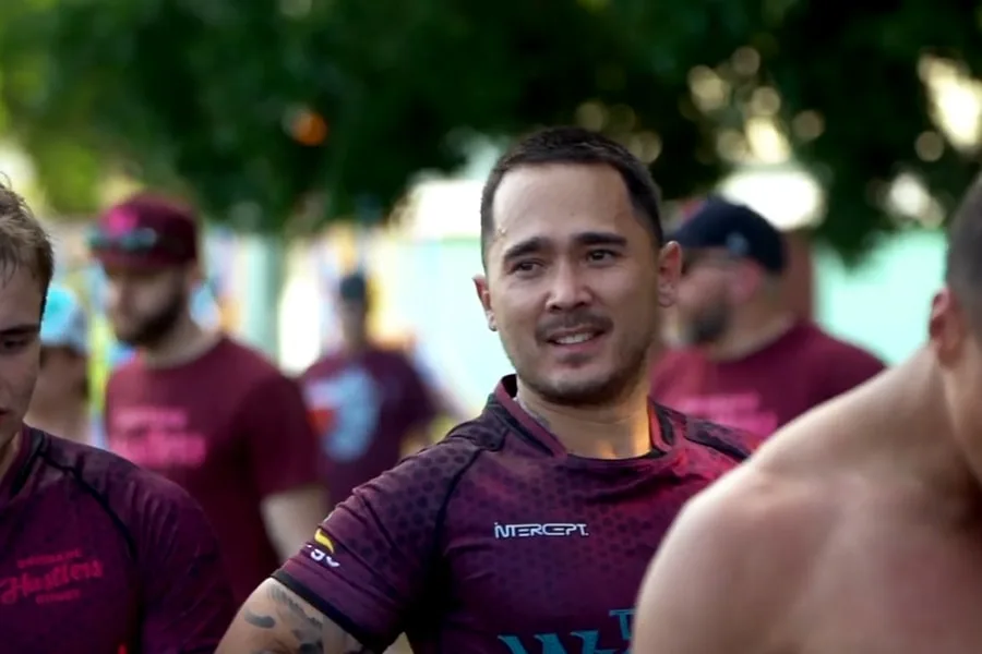 brisbane hustlers gwyn man in rugby uniform surrounded by teammates