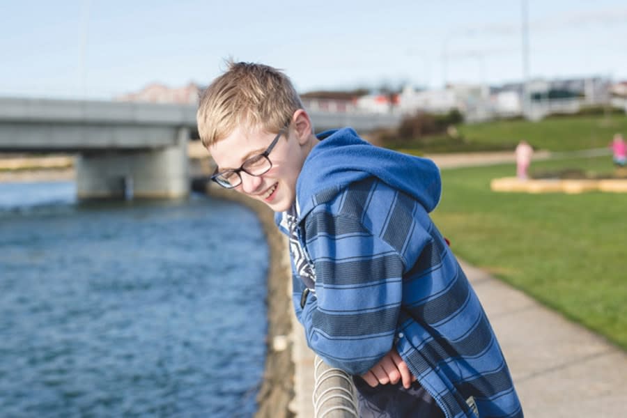 Boy leaning on railing looking at water