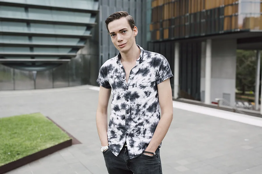 Young man in tie dye shirt standing in front of university 2