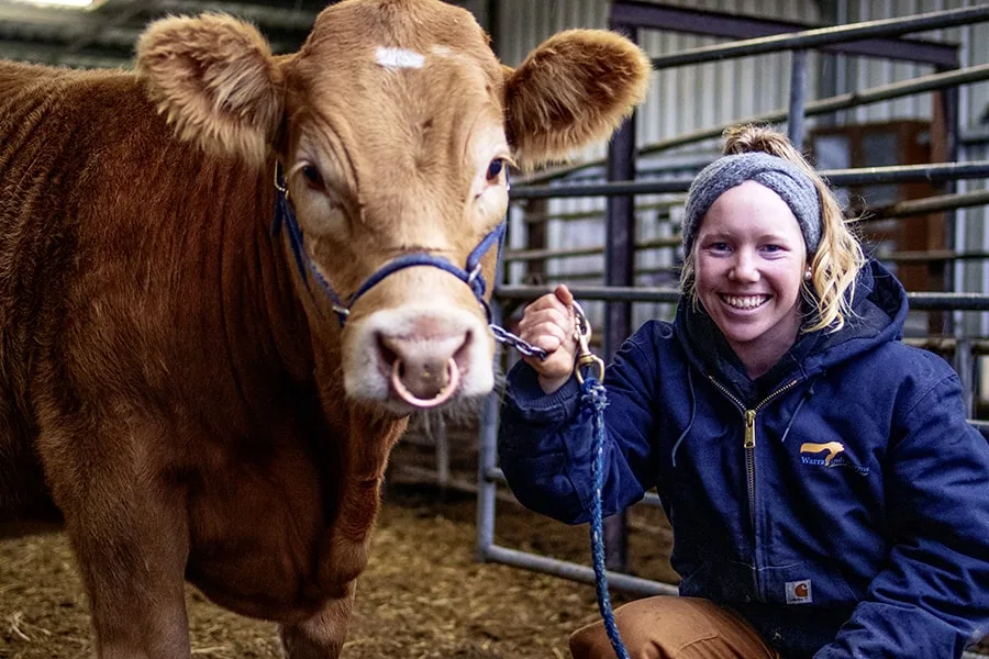 Lu girl smiling in barn with cow next to her