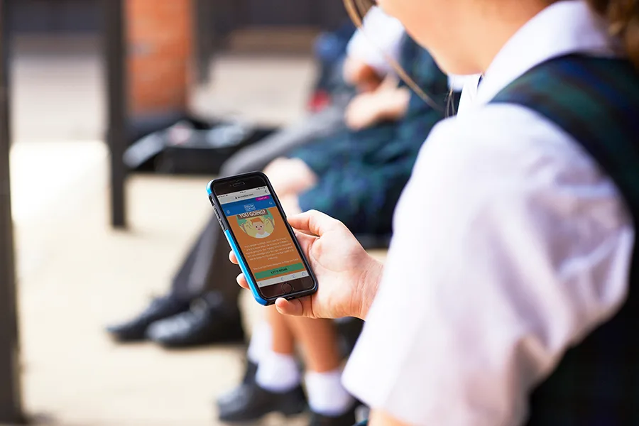 Young person in school uniform holding phone