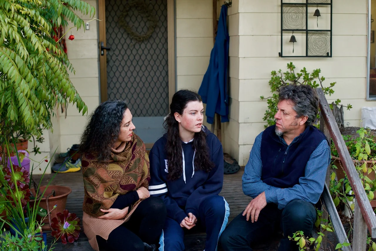 mother and father talking to daughter on front steps