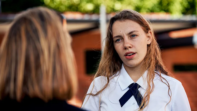 a teenager listening with the back of a parents head in the foreground