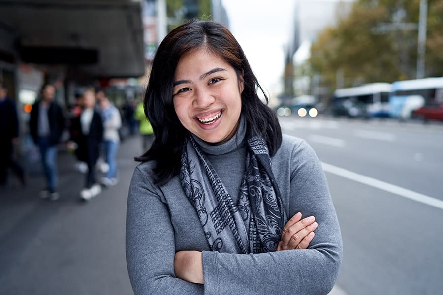 Monica girl smiling with arms crossed city streets behind her