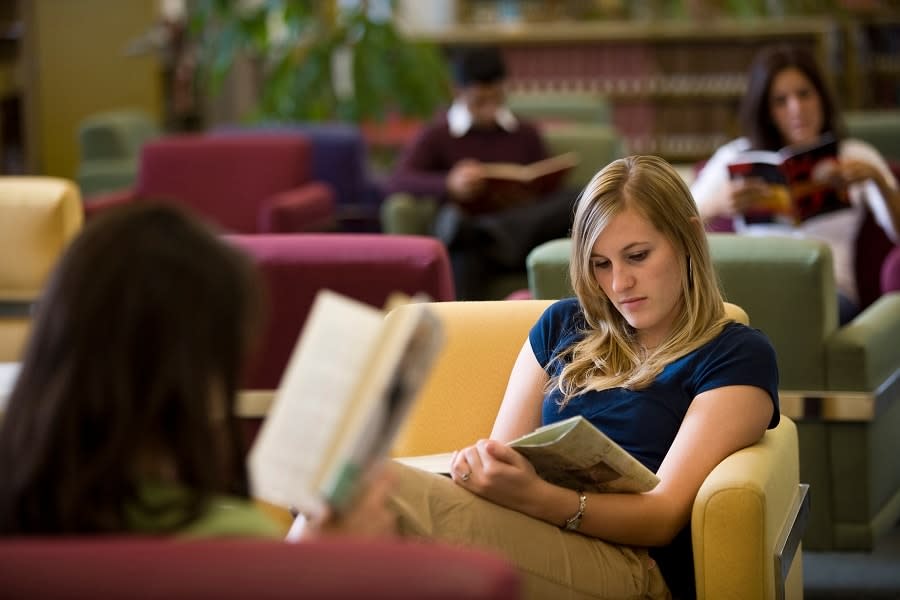 Girl in blue shirt reading in library