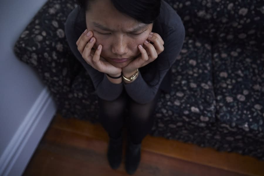 Girl in grey shirt with head in hands sitting on lounge