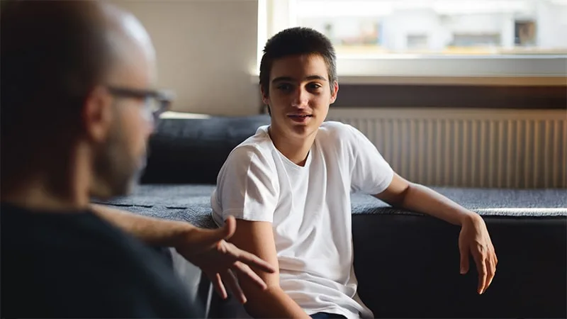 father and son sitting on couch talking