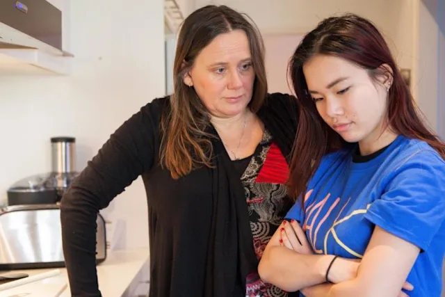 Hija con la espalda a la madre y los brazos cruzados en la cocina