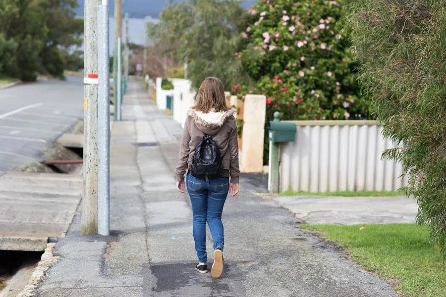 Girl walking away on sidewalk