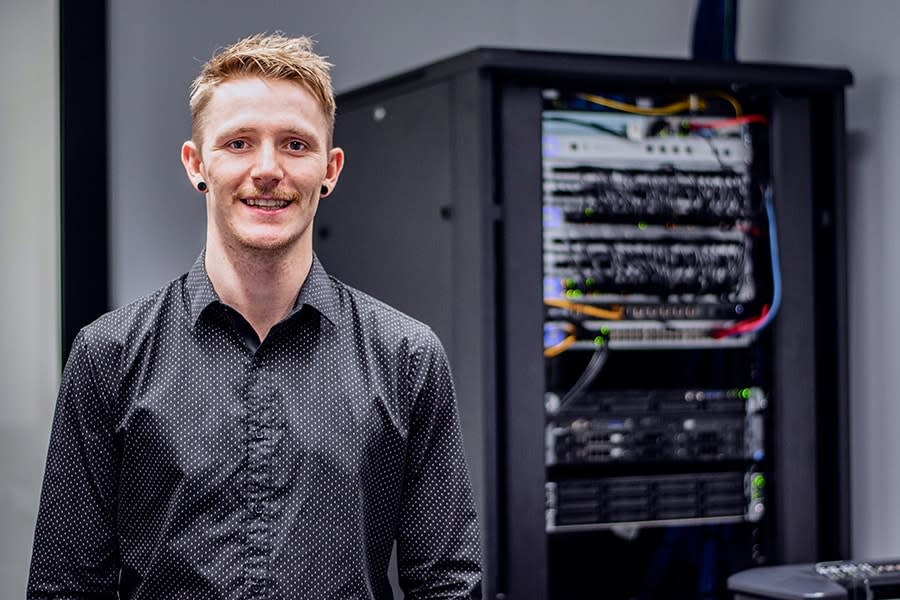 Brodie guy in button up collared shirt with office server behind him