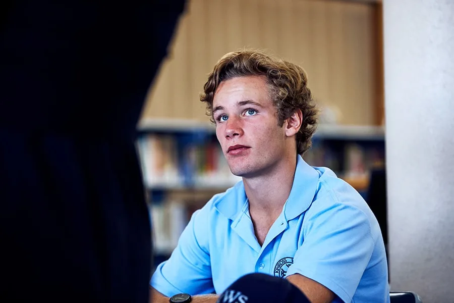 student sits in classroom looking at camera