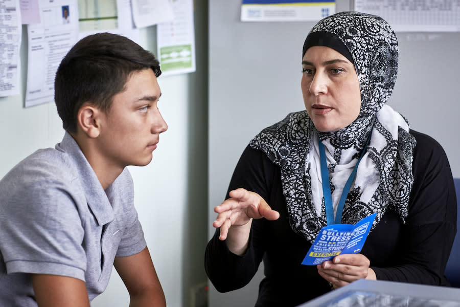 A counsellor talking to a young man and showing him a leaflet