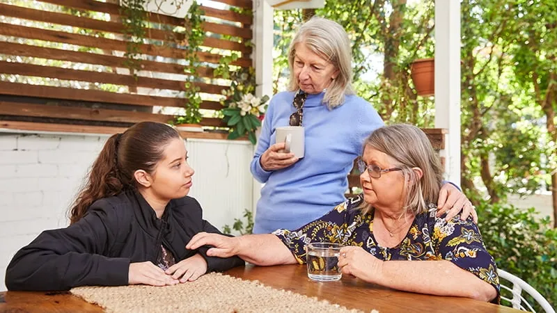 teenage girl being supported by two women