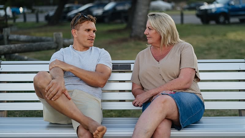 man and woman sitting on bench talking