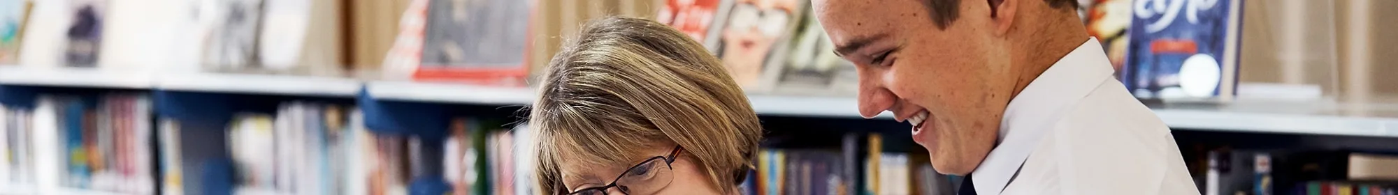 teacher and student in library looking at book topic page