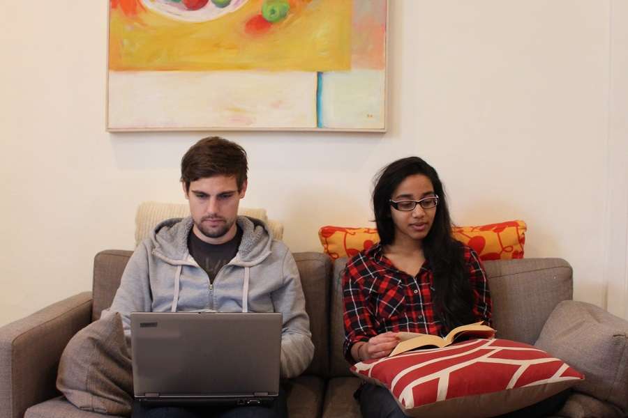 girl and guy sitting on lounge with artwork behind them