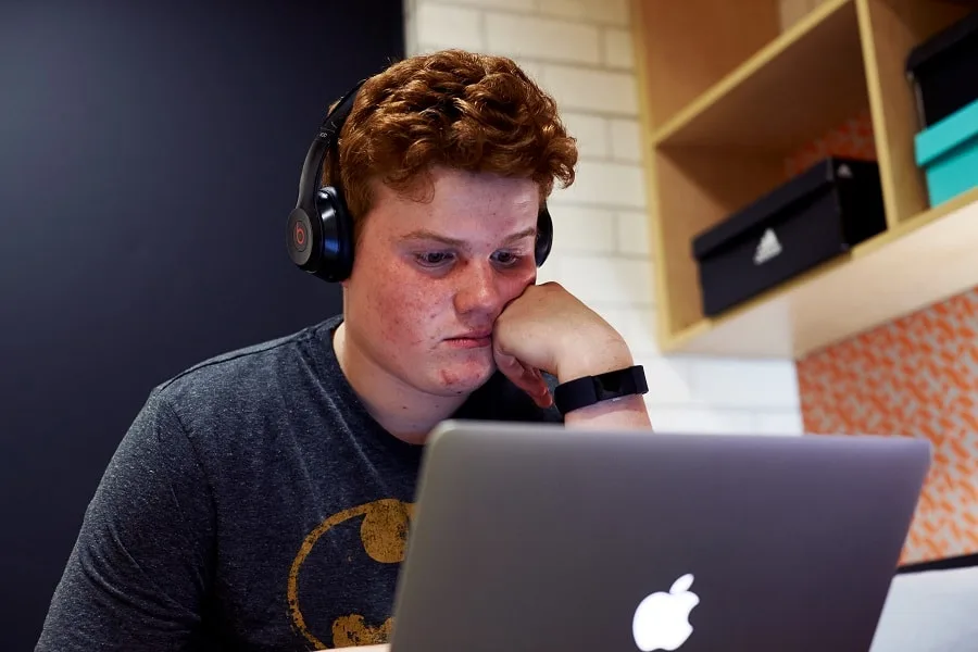 boy with headphones on silver laptop in room
