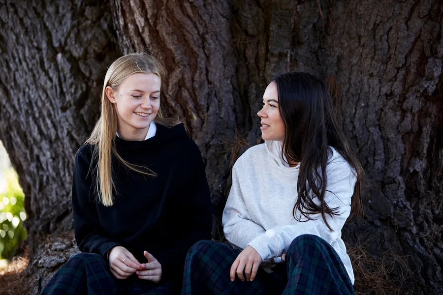 Two young woman sitting outside talking