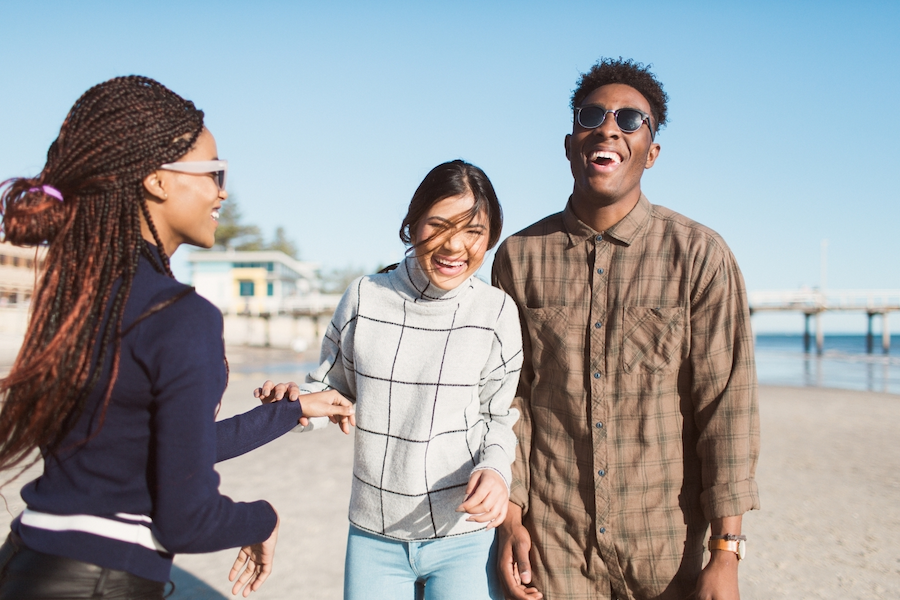 Three friends laughing on a beach