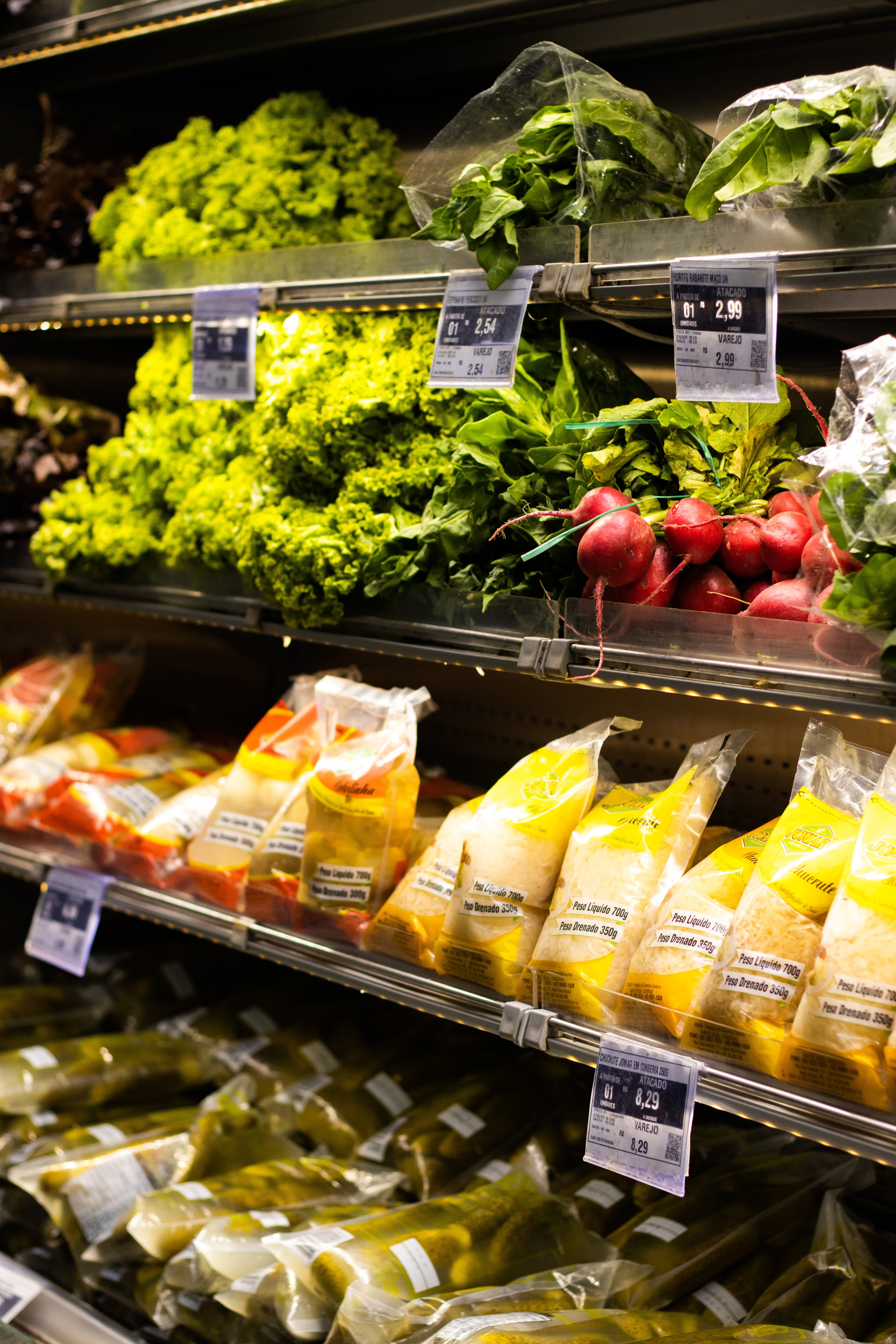 Picture of the vegetable section in an Italian supermarket including radish, iceberg salad, grated potatoes and carrots