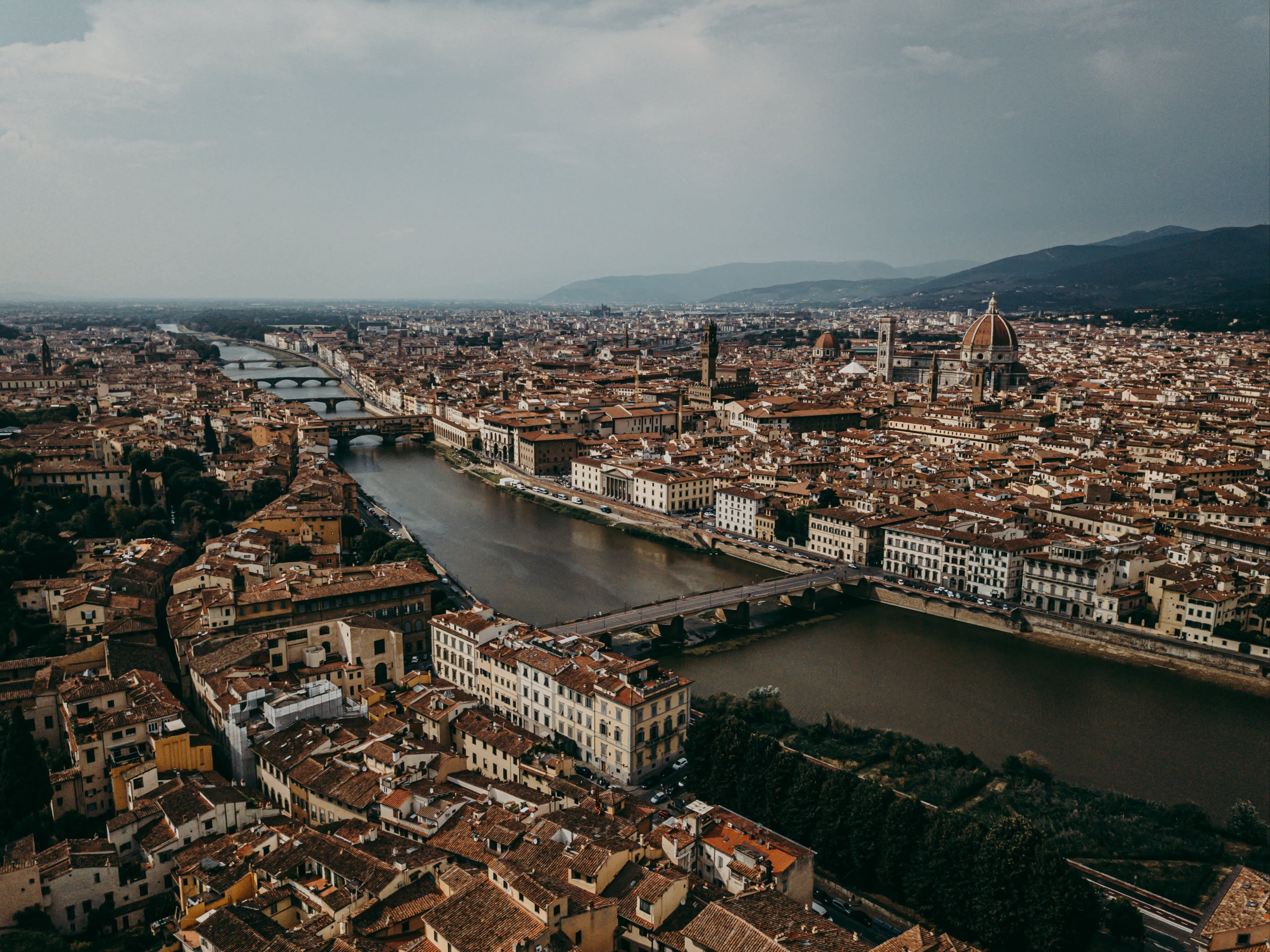 A picture of Florence from a bird's eye view showing both sides of the city, the Cathedral of Santa Maria del Fiore and the Arno river