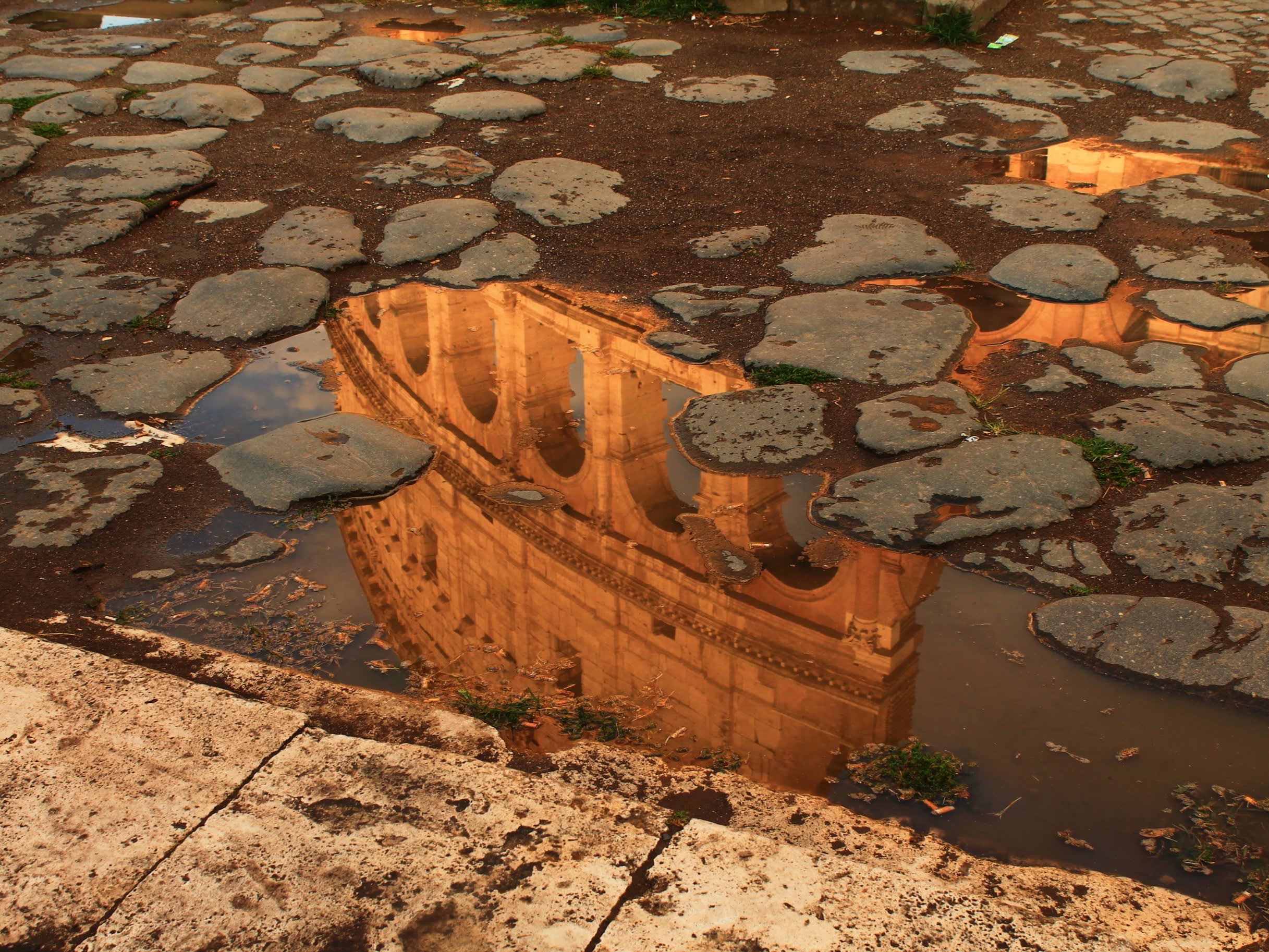 reflection of the Colosseum in a puddle