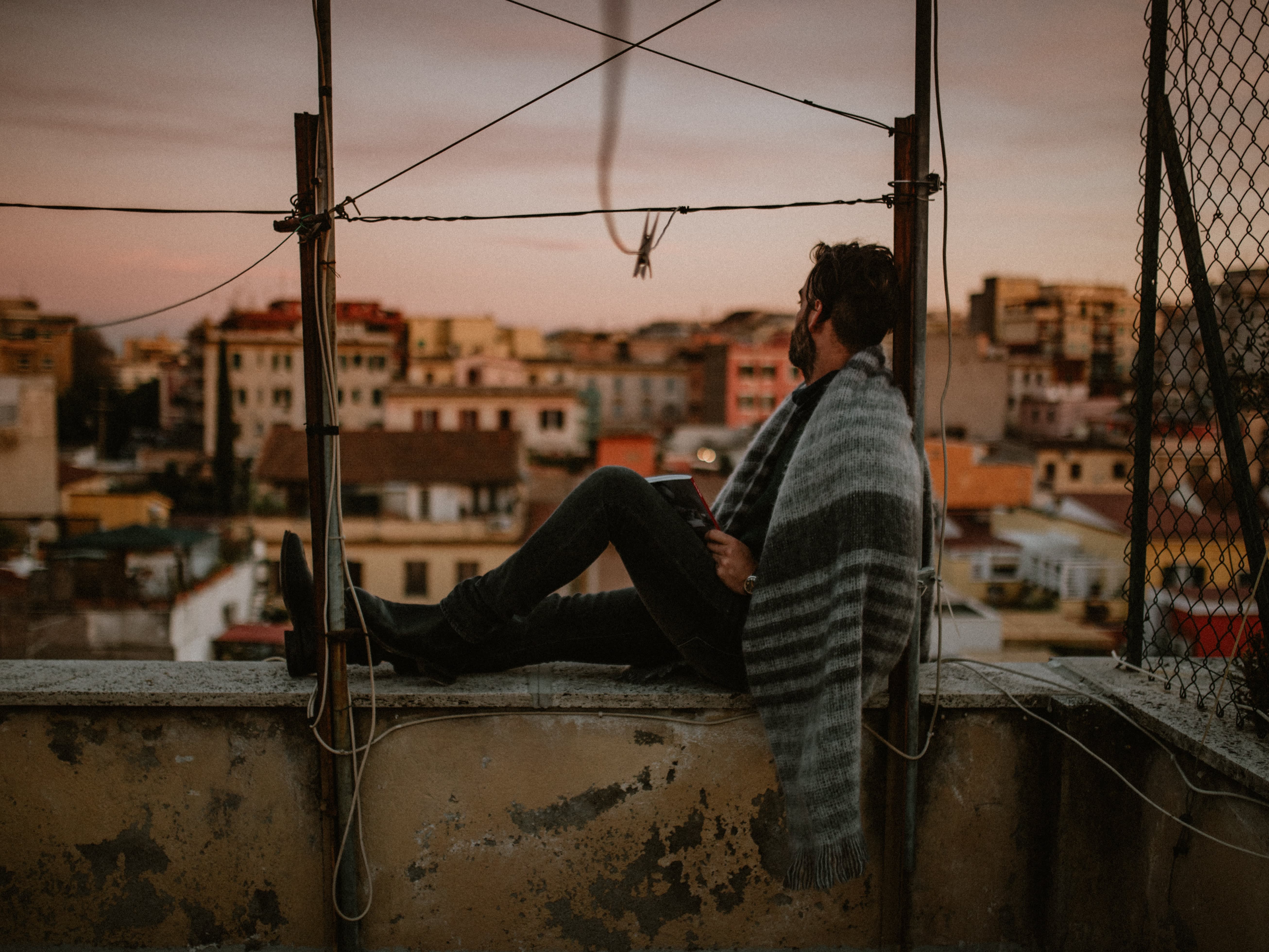 man sitting with a blanket above cityscape