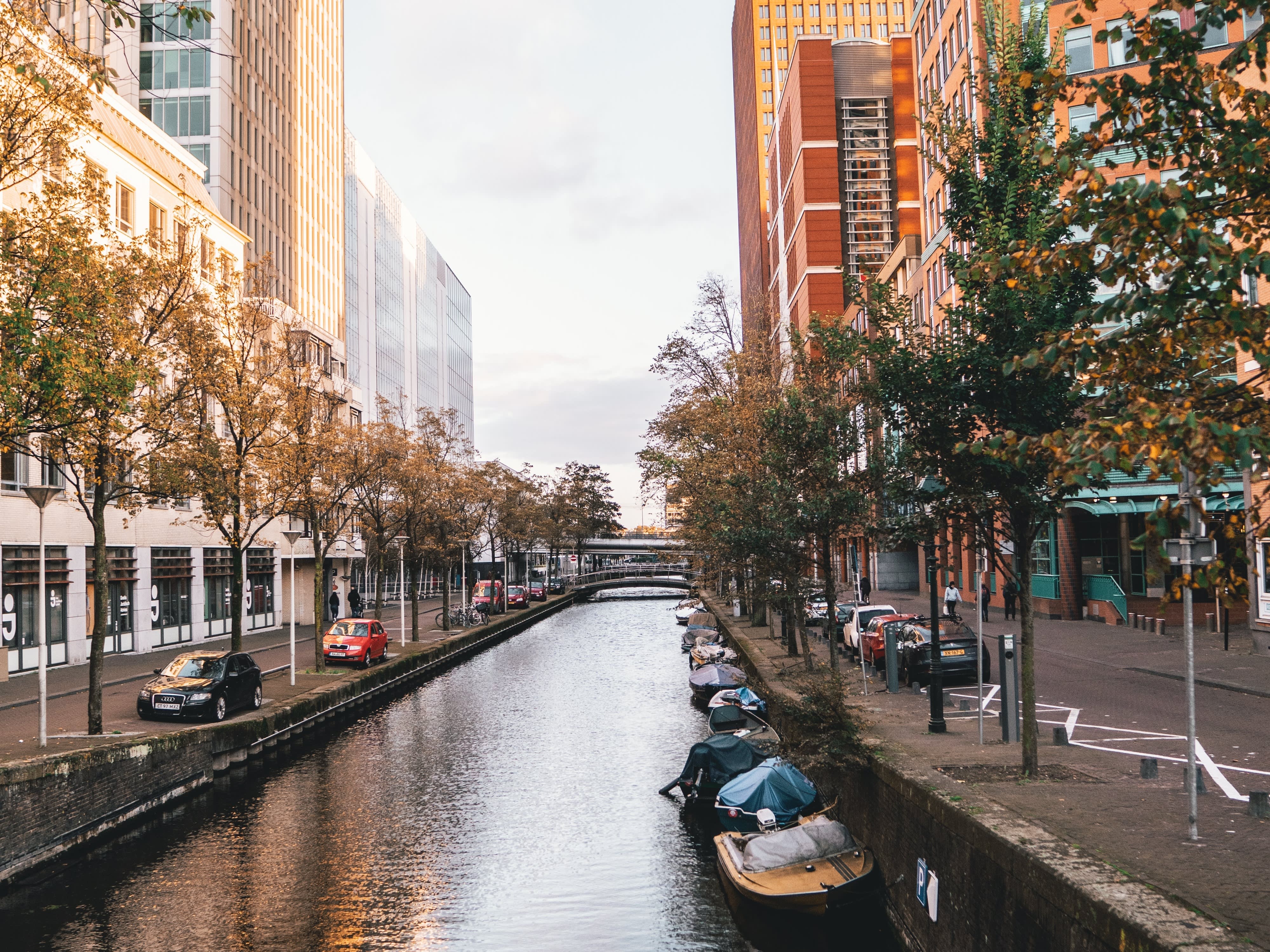 Picture of a canal with boats in The Hague, with skyscrapers along it