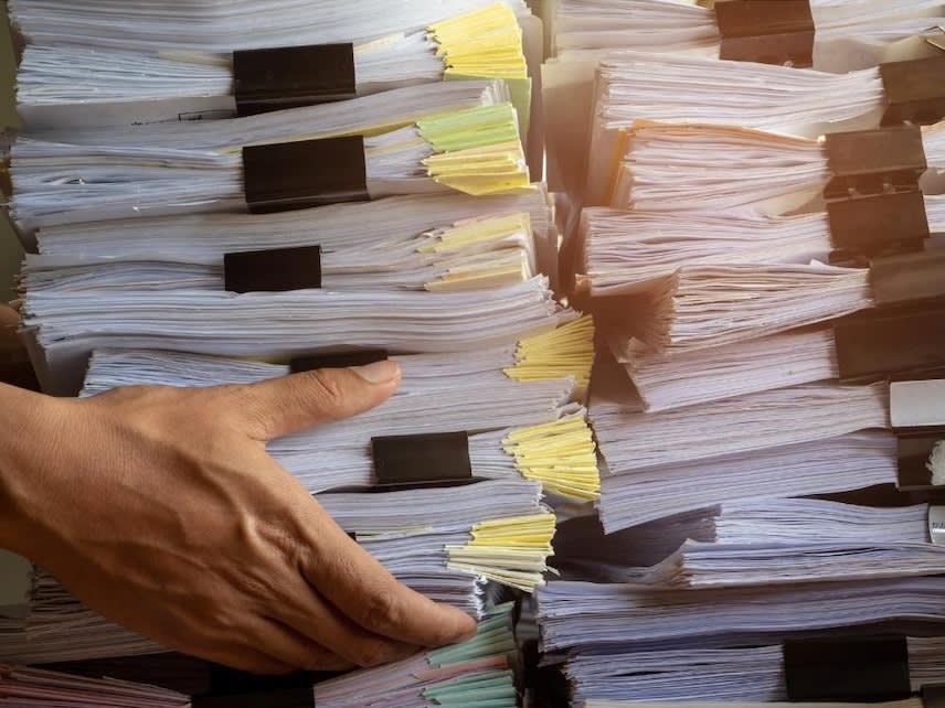 A person placing a pile of documents next to another pile of documents 